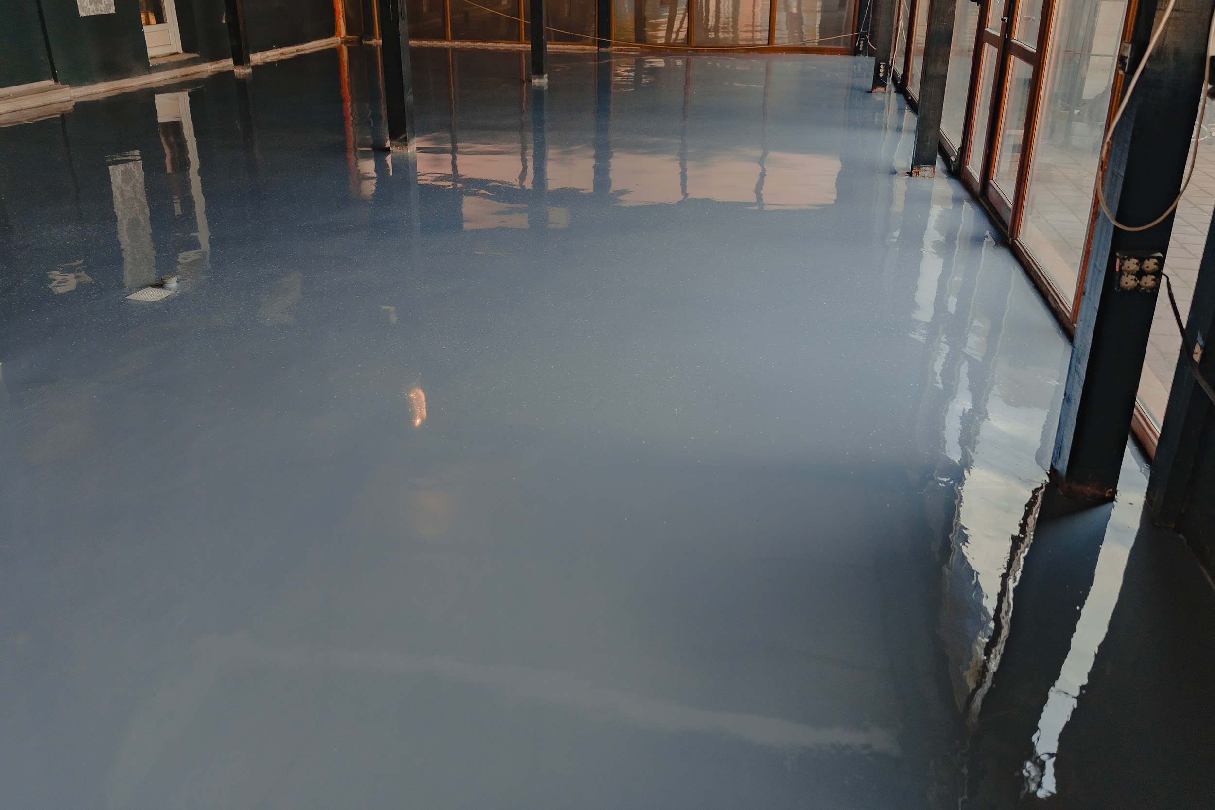 Plancher époxy gris lustré le long d’un mur vitré